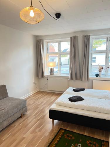 a bedroom with a bed and a couch and windows at Spacious Apartment Near City & Åløkke Forest in Odense