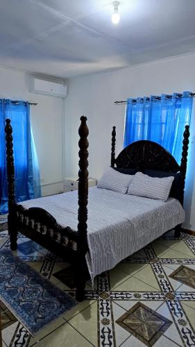 een slaapkamer met een houten bed en blauwe gordijnen bij NR Investments in Kingstown