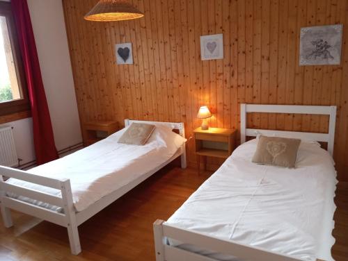 deux lits dans une chambre aux murs en bois dans l'établissement Chez Marinette, à Saint-Jean-Saint-Nicolas