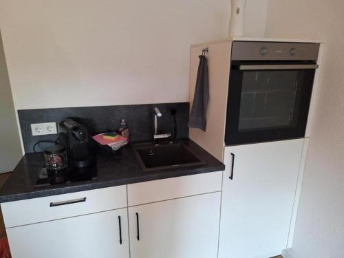 Una pequeña cocina con fregadero y microondas. en Arpartement Deluxe 2 mit balkon prüm, en Weinsheim