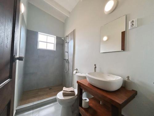 a white bathroom with a sink and a toilet at Oasis Boutique Resort - Magnesium zwembad in Willemstad