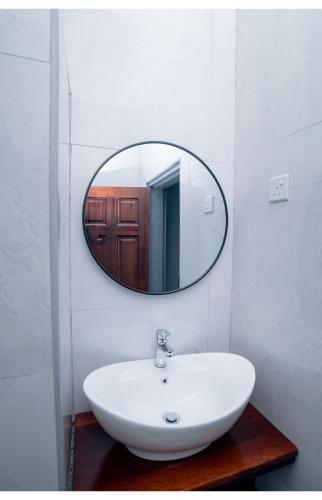 a bathroom with a white sink and a mirror at Akwaaba Apartments in Chipata