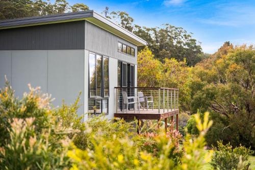 a small house with a deck in the woods at Tranquil Getaway in Tinderbox in Tinderbox