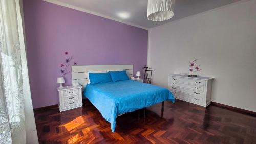 a bedroom with a blue bed and purple walls at Casa Kendra in Montegrotto Terme
