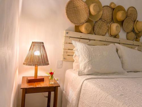 une chambre avec un lit et une table avec une lampe dans l'établissement Maruê Guesthouse Porto de Pedras, à Porto de Pedras