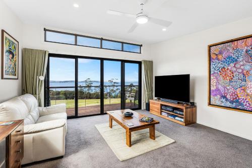 a living room with a couch and a flat screen tv at Tranquil Getaway in Tinderbox in Tinderbox