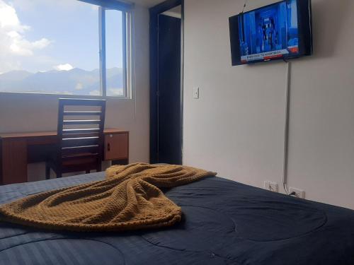 a bedroom with a bed and a tv on the wall at Acevedo Inn Cerca a la embajada Americana , Corferias, G 12, U Nacional, Movistar Arena , Claro Eventos, a 30 minutos del Aeropuerto, Cerca al Can y a la Clinica Meredy contacto trescientosdoscautroseistrescerosieteochoseis in Bogotá