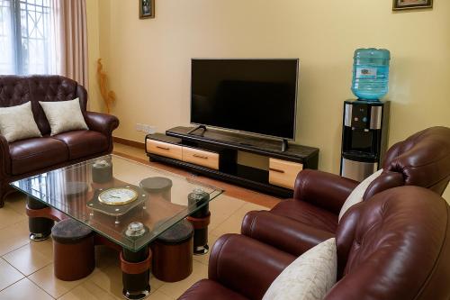 a living room with leather furniture and a flat screen tv at Bonaventure Apartment A in Kisumu