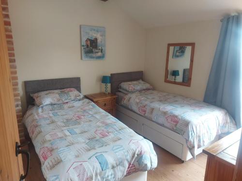 ein Schlafzimmer mit zwei Betten und einem Spiegel in der Unterkunft Coastline cottage in Pakefield