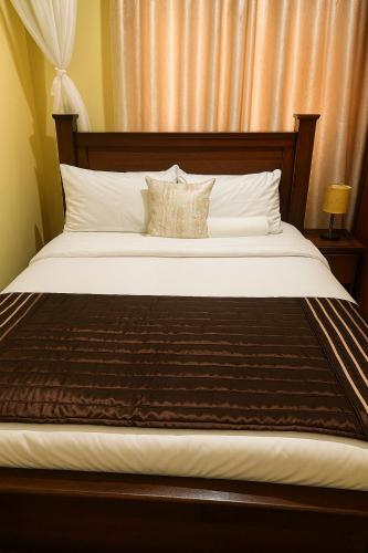 a bedroom with a large bed with a wooden headboard at Bonaventure Apartment A in Kisumu