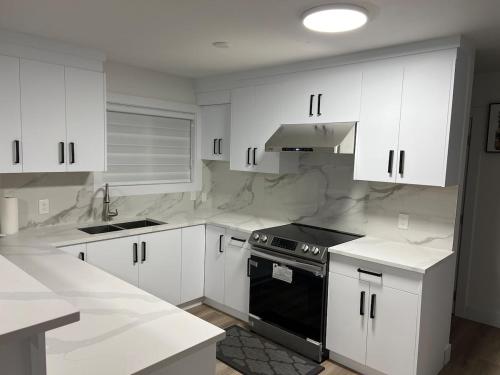 a kitchen with white cabinets and a black stove at Ricky's Apartment in Delta