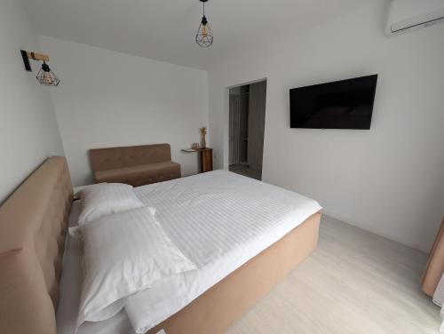a white bedroom with a bed and a flat screen tv at La Belle Mouette in Somova