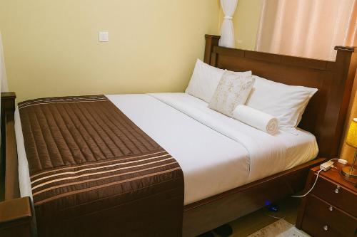 a bedroom with a large bed with white sheets and pillows at Bonaventure Apartment A in Kisumu