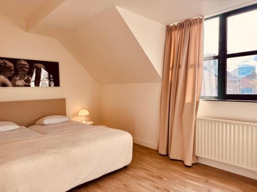 a bedroom with a bed and a large window at Secondo Piano Hasselt in Hasselt