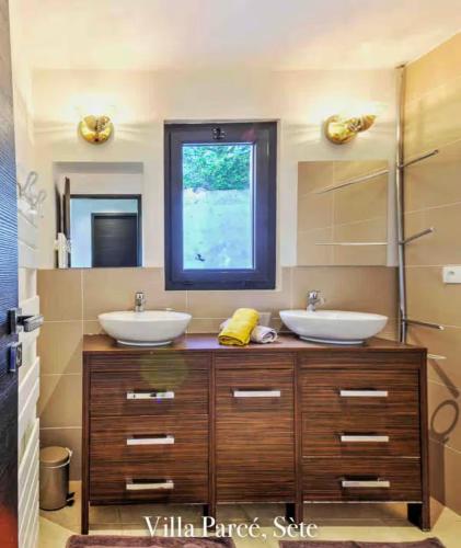 a bathroom with two sinks and a large mirror at Villa vue mer in Sète