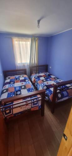 two beds in a room with blue walls at cabaña elquimilen in Vicuña