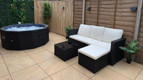 a patio with a jacuzzi tub and a couch and a chair at The Hidden Garden Gate Cabin in Wallington