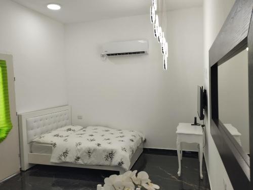 a white bedroom with a bed and a television at פנינה בבקעה - בקרבת עמק המייענות בקעת הירדן in Bet Sheʼan