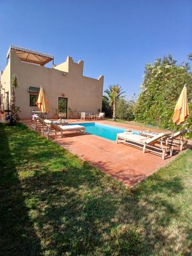 a house with a swimming pool with chairs and umbrellas at فيلا رياض عمران in Douar Blidene