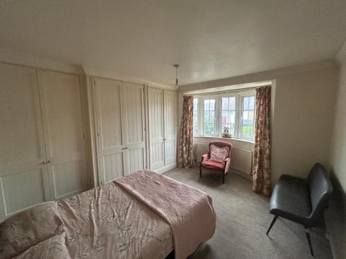 a bedroom with a bed and a chair and a window at Eastcote 1st Floor Retreat 2 Bedroom Suite with Kitchen and Bathroom 2mins to Tube 20mins to Heathrow and Wembley 25mins Drive to Harry Potter World FREE PARKING in Eastcote