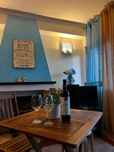 a bottle of wine and two glasses on a wooden table at Casa da Areia Branca in Bolembre de Baixo