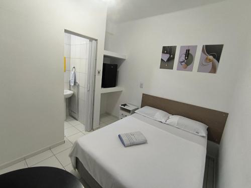 a white bedroom with a bed and a bathroom at Pousada Mar e Luz in Ilha Comprida