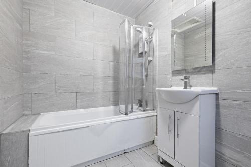a white bathroom with a tub and a sink at Large 5-Bed Home, Free Parking, Perfect for Groups in Nottingham