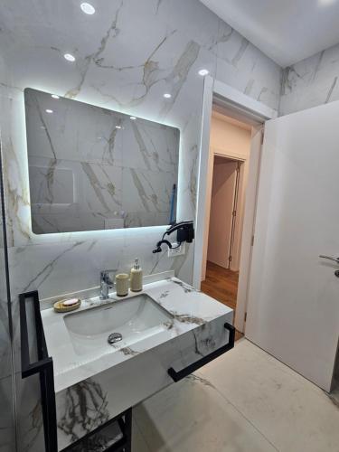 a white bathroom with a sink and a mirror at Univers City Apartment in Tirana