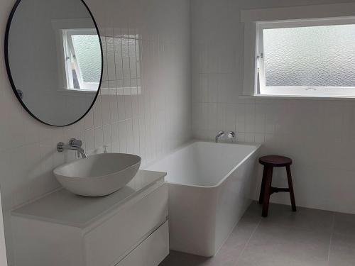 een badkamer met een wastafel, een bad en een spiegel bij Inner city Sanctuary in Gisborne