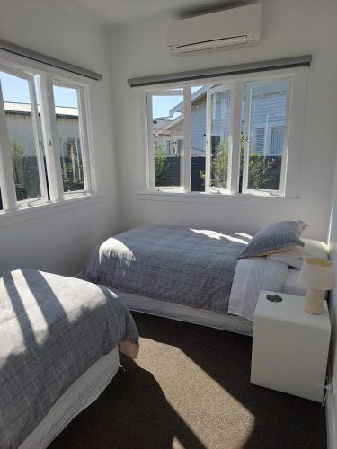 a bedroom with two beds and two windows at Inner city Sanctuary in Gisborne
