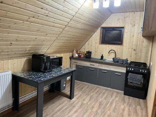 eine Küche mit einem Tisch, einer Mikrowelle und einem Herd in der Unterkunft Casa Ionuț și Sofia in Podu Dîmboviţei