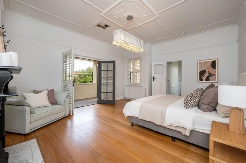 een witte slaapkamer met een bed en een bank bij Poolside at Kindrogan - St Kilda in Melbourne
