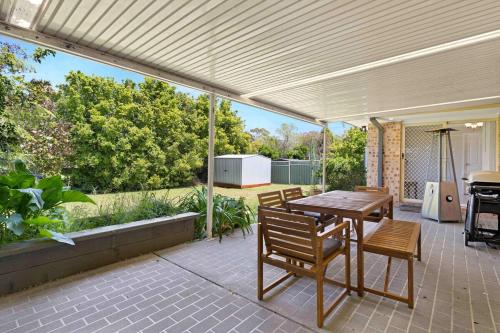 a patio with a table and chairs and a grill at Bay Breeze Cottage in Callala Bay