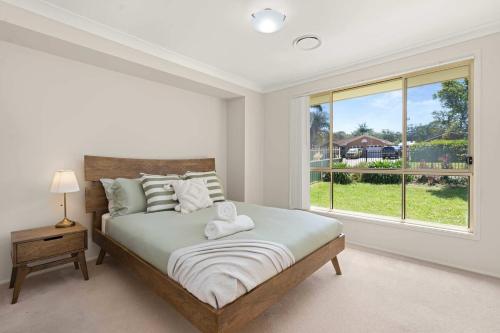 a bedroom with a large bed and a window at Bay Breeze Cottage in Callala Bay