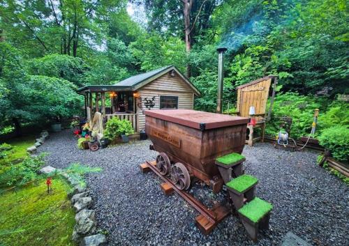 a toy train sitting in front of a small shed at The Miners Log Cabin in Blaina