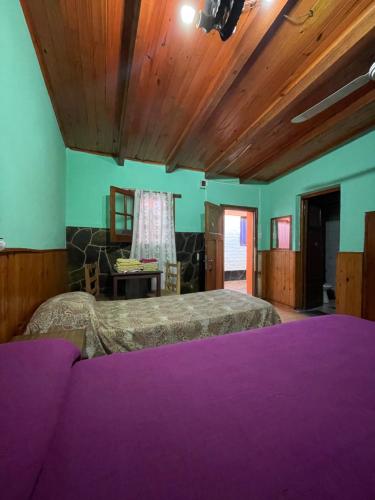 a bedroom with purple beds and a wooden ceiling at Hosteria Rosales in Trapiche