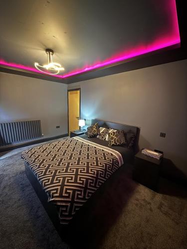 a bedroom with a bed with pink lights on it at SK Stays Modern Luxury Home With Jacuzzi Bath & Cinema Room in Shipley