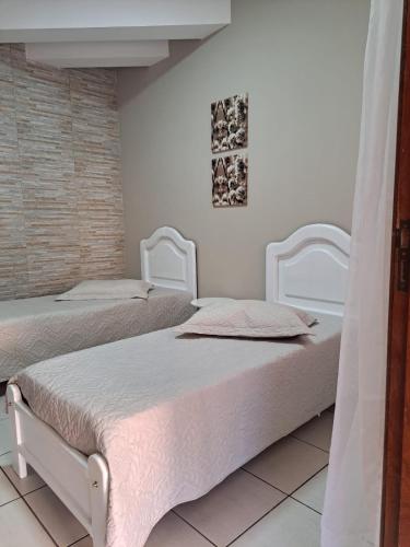 two beds in a room with white walls at Quarto confortável em Diamantina in Diamantina