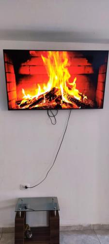 une télévision suspendue sur un mur avec une cheminée dans l'établissement casa rústica, à Ica