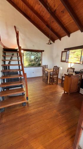 a living room with a staircase and a table and chairs at Cabaña de montaña con pileta en hermoso predio in Villa Yacanto