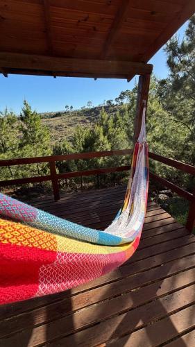 a colorful hammock on a wooden deck with a view at Cabaña de montaña con pileta en hermoso predio in Villa Yacanto