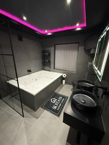 a large bath tub in a bathroom with purple lights at SK Stays Modern Luxury Home With Jacuzzi Bath & Cinema Room in Shipley