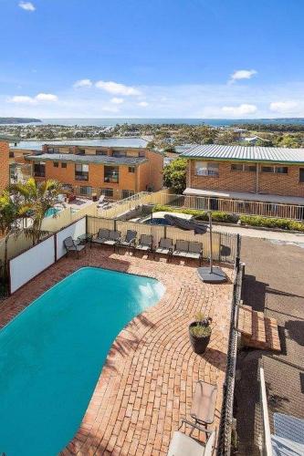 a swimming pool with chairs and a building at Hydra 2 bedroom Holiday Unit in Merimbula