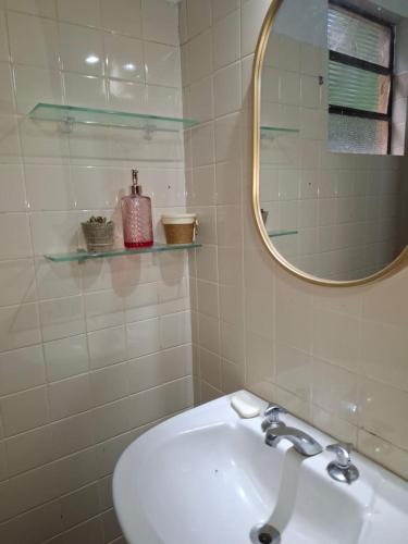 a white bathroom with a sink and a mirror at Chalé Dedo de Deus in Guapimirim
