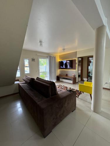 Una sala de estar con un sofá marrón y una silla amarilla. en Casa 2 dormitórios, en Passo de Torres