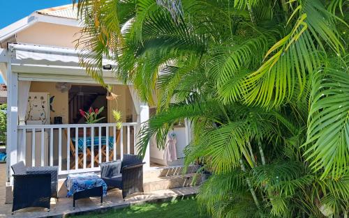 une terrasse couverte d'une maison avec des chaises et un palmier dans l'établissement Bungalow dans Résidence Fleurie, à Saint-François