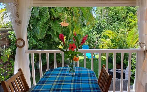 - une table avec un vase de fleurs sur une terrasse couverte dans l'établissement Bungalow dans Résidence Fleurie, à Saint-François