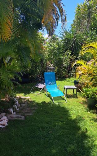 a blue chair and a bench in the grass at Bungalow dans Résidence Fleurie in Saint-François