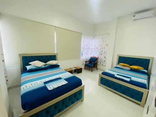 a bedroom with two beds and a chair at Apartamento Ciudad del Surf Montañita in Montañita