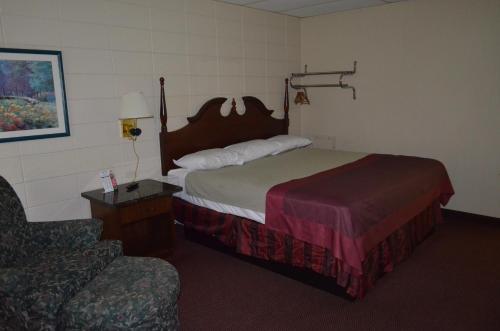 a hotel room with a bed and a chair at Grand Inn Fargo in Fargo